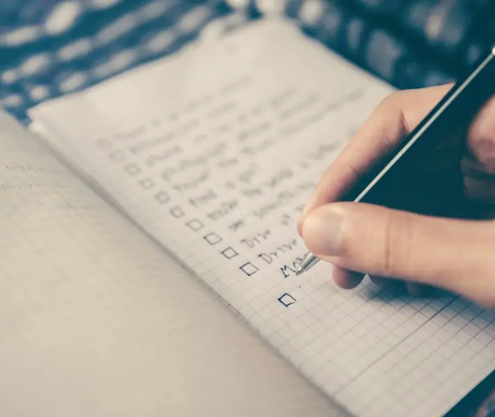 Hand ticking off items on a handwritten checklist