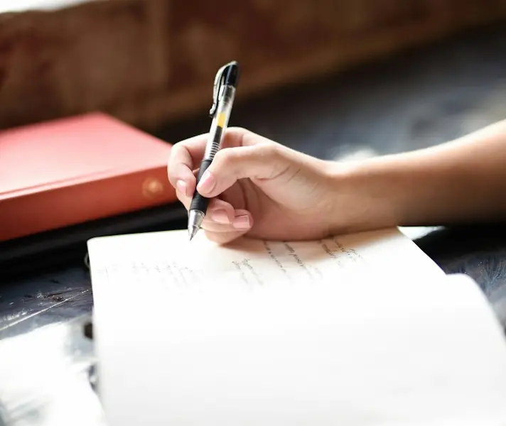 Person writing notes by hand in a notebook