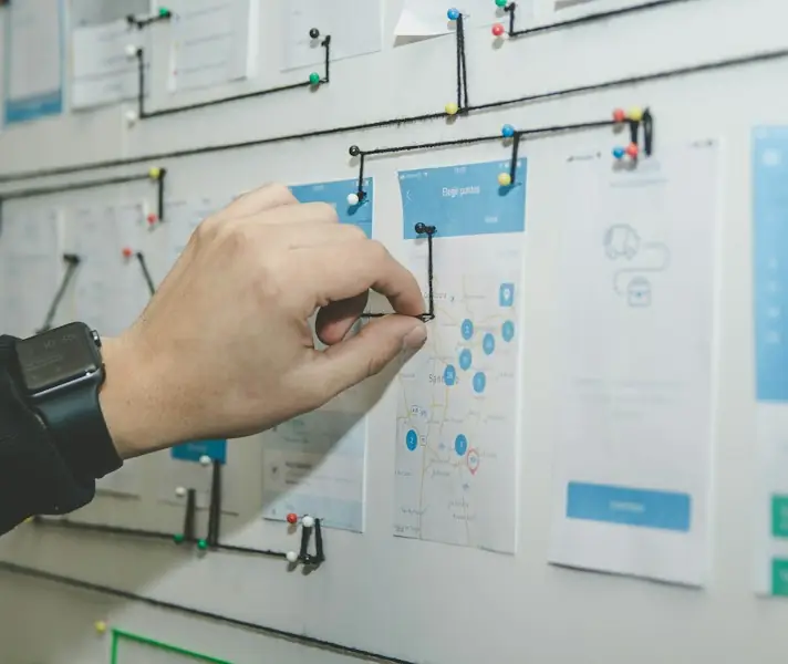 Person arranging sticky notes and wireframes on a whiteboard